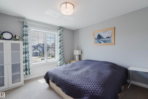 Bright room featuring a large window with white framing, light gray walls, and light-colored carpeting - 3571 Keswick Boulevard, Edmonton, AB - Indoor Photo Showing Bedroom