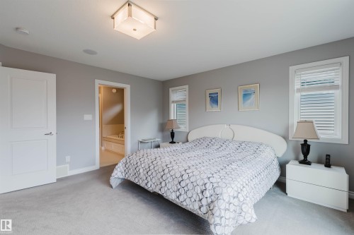 Carpeted bedroom featuring two windows with blinds, a ceiling-mounted light fixture, and a built-in ceiling speaker - 3571 Keswick Boulevard, Edmonton, AB - Indoor Photo Showing Bedroom