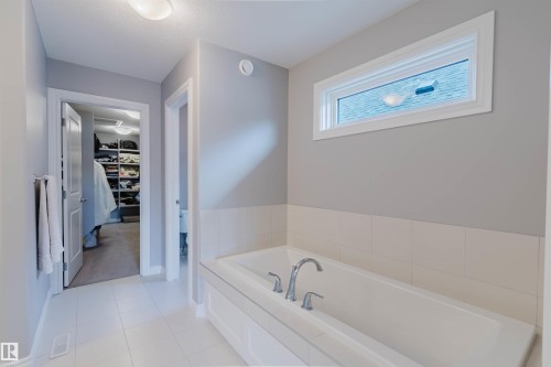 Soaking tub with chrome fixtures, set against a tiled wainscoting - 3571 Keswick Boulevard, Edmonton, AB - Indoor Photo Showing Bathroom