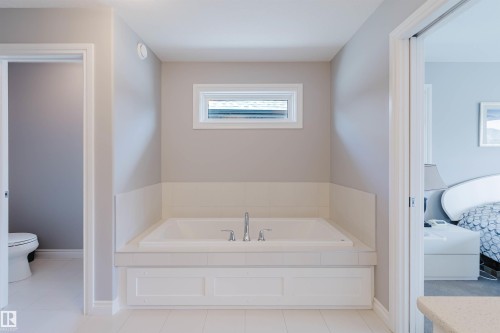 Built-in soaking tub with deck-mounted chrome fixtures, white tile surround, and a horizontal window - 3571 Keswick Boulevard, Edmonton, AB - Indoor Photo Showing Bathroom