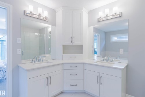 Dual vanity featuring white shaker-style cabinetry, white countertops, undermount sinks, and brushed nickel hardware - 3571 Keswick Boulevard, Edmonton, AB - Indoor Photo Showing Bathroom