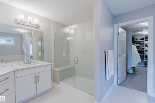 Bathroom featuring a double vanity with white cabinetry, a large mirror, and a glass-enclosed shower with a built-in bench - 3571 Keswick Boulevard, Edmonton, AB - Indoor Photo Showing Bathroom