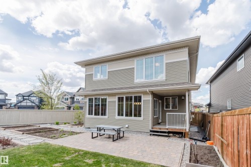 Rear exterior featuring horizontal siding, multiple windows, and a paved patio area - 3571 Keswick Boulevard, Edmonton, AB - Outdoor