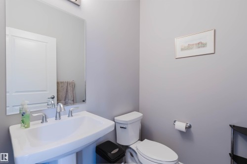 Pedestal sink with chrome faucet, toilet, and mounted mirror - 3571 Keswick Boulevard, Edmonton, AB - Indoor Photo Showing Bathroom