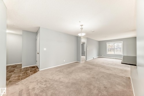 Living area featuring light grey walls, a carpeted floor, and a window providing natural light - 101 530 Watt Boulevard, Edmonton, AB - Indoor Photo Showing Other Room