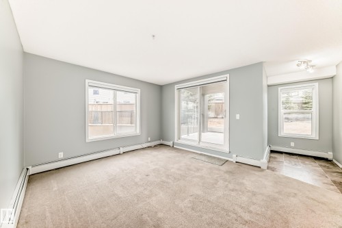 Spacious living area featuring light-colored carpet, grey walls, and white trim - 101 530 Watt Boulevard, Edmonton, AB - Indoor Photo Showing Other Room