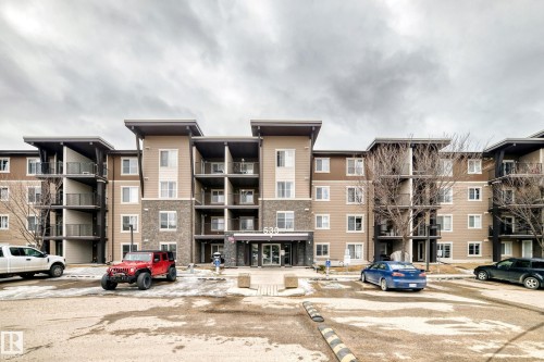 The property features a multi-story building with a neutral color palette, incorporating tan siding and stone accents - 101 530 Watt Boulevard, Edmonton, AB - Outdoor With Facade