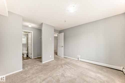 This room features light grey walls and light grey carpet flooring - 101 530 Watt Boulevard, Edmonton, AB - Indoor Photo Showing Other Room