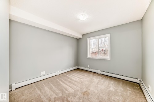 This room features light grey walls, a window with a white frame, and beige patterned carpeting - 101 530 Watt Boulevard, Edmonton, AB - Indoor Photo Showing Other Room
