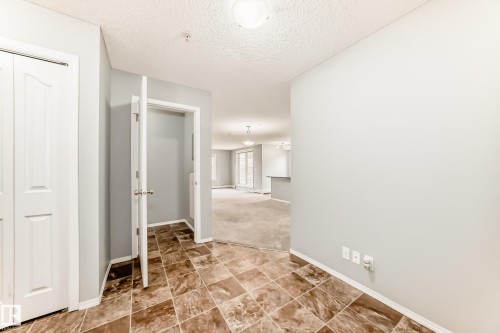 Entrance featuring patterned floor tiles and light-colored walls, leading into a carpeted interior - 101 530 Watt Boulevard, Edmonton, AB - Indoor Photo Showing Other Room
