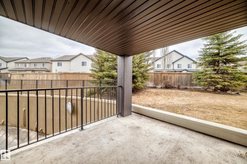 The property features a covered patio with a concrete surface and a black metal railing - 101 530 Watt Boulevard, Edmonton, AB - Outdoor With Exterior