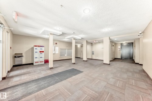 The property features a spacious common area with tiled flooring, recessed lighting, and access to mailboxes - 101 530 Watt Boulevard, Edmonton, AB - Indoor Photo Showing Other Room