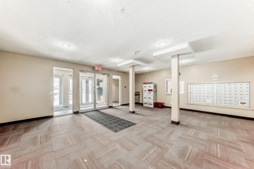 The property features an entryway with glass doors and a patterned floor - 101 530 Watt Boulevard, Edmonton, AB - Indoor Photo Showing Other Room