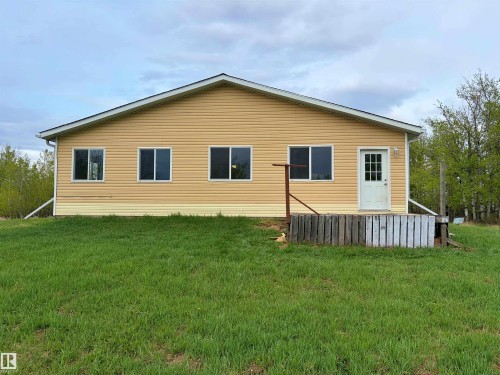 Single-story exterior featuring yellow horizontal siding, a white entry door with glass panes, and multiple windows with white trim - 60016 Rr 41, Rural Barrhead County, AB - Outdoor