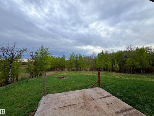 Expansive natural landscape featuring a wooden platform, open green space, and a perimeter of mature deciduous trees - 60016 Rr 41, Rural Barrhead County, AB - Outdoor With View