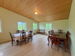 Spacious room featuring a light wood-finish flooring, a vaulted wood-paneled ceiling, and multiple windows - 