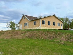 Ranch-style exterior with yellow siding and a brown shingle roof - 