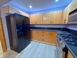 Kitchen featuring light wood cabinetry, dark speckled countertops, and a subway tile backsplash - 