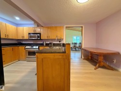 Kitchen featuring light wood-finish cabinetry, dark countertops, and stainless steel appliances including a range and microwave - 