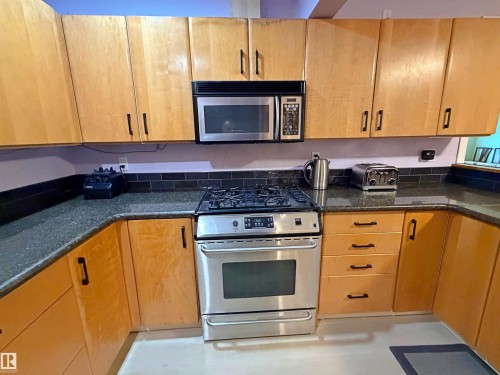 Kitchen featuring light wood cabinetry, dark speckled countertops, and a subway tile backsplash - 60016 Rr 41, Rural Barrhead County, AB - Indoor Photo Showing Kitchen With Double Sink