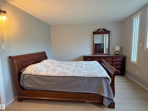 Bedroom featuring light wood-finish flooring, a wall-mounted sconce, and two tall vertical windows with white trim - 60016 Rr 41, Rural Barrhead County, AB - Indoor Photo Showing Bathroom