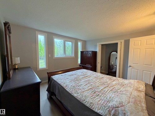 Spacious room featuring light gray walls, white trim, and wood-finish flooring - 60016 Rr 41, Rural Barrhead County, AB - Indoor Photo Showing Bedroom