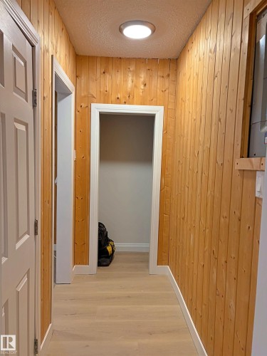 Hallway featuring wood paneling walls, light wood-finish flooring, white trim, recessed ceiling lighting, and white paneled doors - 60016 Rr 41, Rural Barrhead County, AB - Indoor Photo Showing Laundry Room