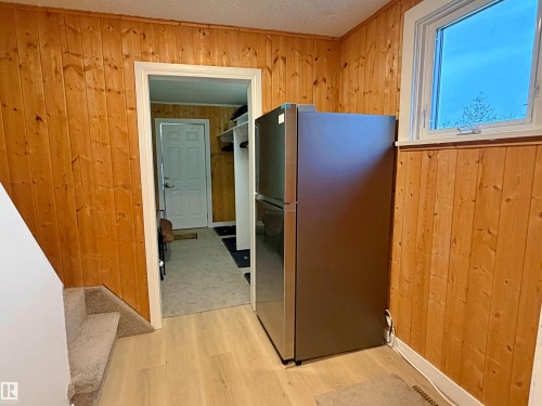 Light wood-finish flooring with vertical wood paneling - 60016 Rr 41, Rural Barrhead County, AB - Indoor Photo Showing Bedroom