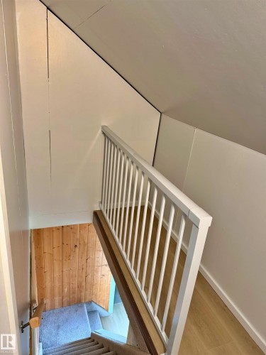 Staircase with white balusters and a wood-finish handrail - 60016 Rr 41, Rural Barrhead County, AB - Indoor Photo Showing Other Room