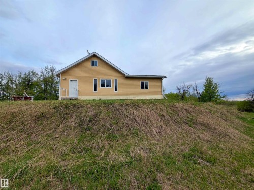 Exterior featuring yellow siding, a white front door, and multiple windows - 60016 Rr 41, Rural Barrhead County, AB - Outdoor