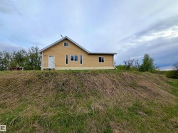 Exterior featuring yellow siding, a white front door, and multiple windows - 