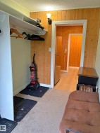 Built-in closet with shelving and hanging rod, tongue-and-groove wood paneling, wall sconce lighting, and wood-finish flooring - 