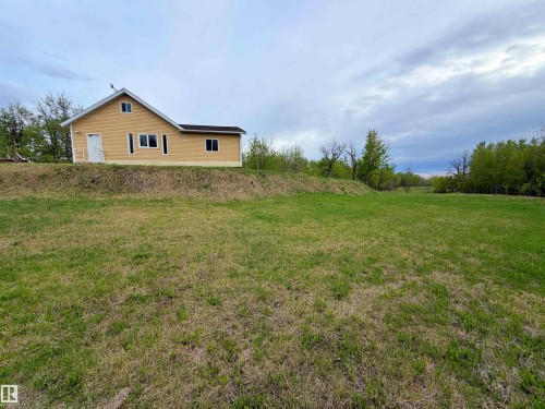 Yellow-sided home with dark shingle roofing positioned on an elevated landscape - 60016 Rr 41, Rural Barrhead County, AB - Outdoor
