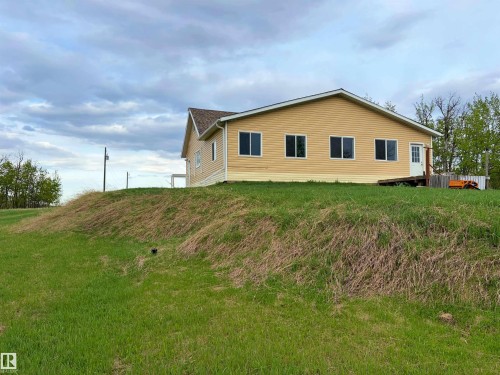 Ranch-style residence featuring yellow horizontal siding, a gabled roofline with brown shingles, and multiple windows - 60016 Rr 41, Rural Barrhead County, AB - Outdoor