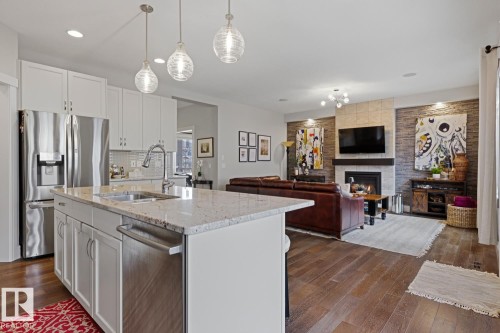 Open-concept living space featuring a gourmet kitchen island with a double basin sink and stainless steel appliances - 1359 Westerra Drive, Stony Plain, AB - Indoor Photo Showing Kitchen With Fireplace With Double Sink With Upgraded Kitchen