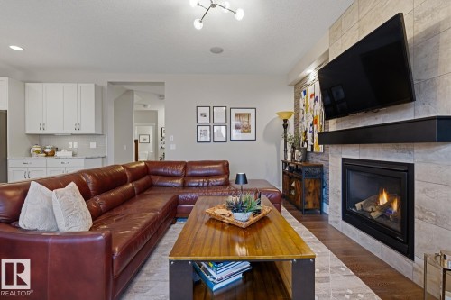 Contemporary living area featuring a built-in fireplace with a tiled surround, a dark wood-finish mantel, and wood-finish flooring - 1359 Westerra Drive, Stony Plain, AB - Indoor Photo Showing Living Room With Fireplace