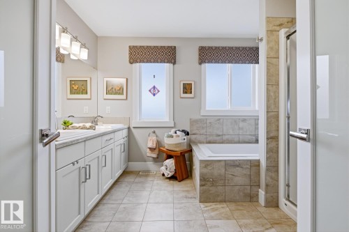 Expansive bathroom featuring a dual sink vanity with white cabinetry and a light-toned countertop, a built-in tub with tile surround, a separate shower enclosure with a glass door, and tiled flooring - 1359 Westerra Drive, Stony Plain, AB - Indoor Photo Showing Bathroom