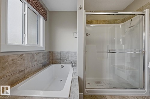 Full-sized bathtub with tiled surround, accompanied by a glass-enclosed shower featuring a built-in seat - 1359 Westerra Drive, Stony Plain, AB - Indoor Photo Showing Bathroom