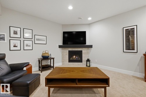 Recessed lighting illuminates a corner fireplace featuring light-toned tile surround and a dark wood mantel - 1359 Westerra Drive, Stony Plain, AB - Indoor Photo Showing Living Room With Fireplace