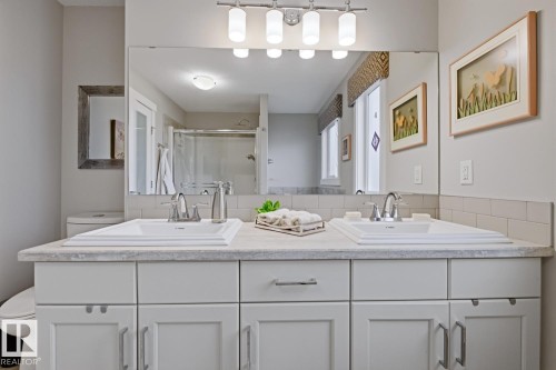 Dual undermount sinks with chrome fixtures set into a light-toned countertop - 1359 Westerra Drive, Stony Plain, AB - Indoor Photo Showing Bathroom