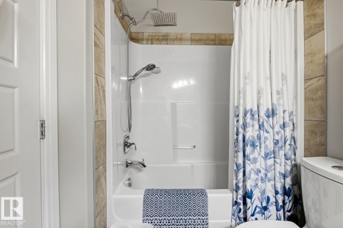 Tub and shower combination featuring a rainfall showerhead, handheld shower fixture, and chrome hardware - 1359 Westerra Drive, Stony Plain, AB - Indoor Photo Showing Bathroom