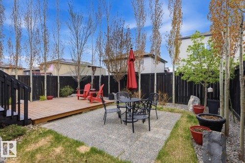 Outdoor living space featuring a wood-finish deck with black railings, a paved patio, and a dark privacy fence - 1359 Westerra Drive, Stony Plain, AB - Outdoor