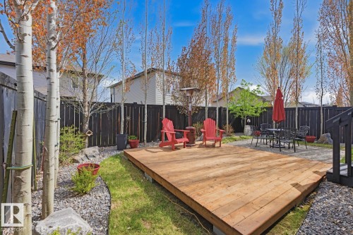Expansive backyard featuring a spacious wood-deck patio, gravel landscaping, manicured lawn, dark privacy fencing, and mature trees - 1359 Westerra Drive, Stony Plain, AB - Outdoor