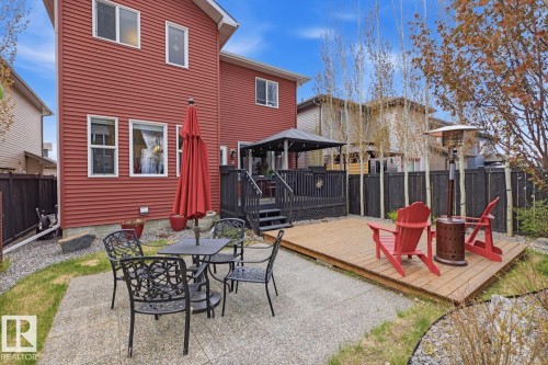 Rear exterior featuring a red siding finish, a multi-level deck with a black gazebo, a ground-level concrete patio, and a separate wooden deck area - 1359 Westerra Drive, Stony Plain, AB - Outdoor With Deck Patio Veranda