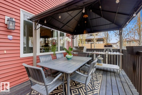 Covered deck featuring dark wood-finish flooring, a black metal gazebo with integrated lighting, and red horizontal siding - 1359 Westerra Drive, Stony Plain, AB - Outdoor With Deck Patio Veranda With Exterior