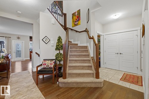 Grand entryway featuring a carpeted staircase with wood handrails, hardwood flooring, and a tiled entry foyer - 1359 Westerra Drive, Stony Plain, AB - Indoor Photo Showing Other Room
