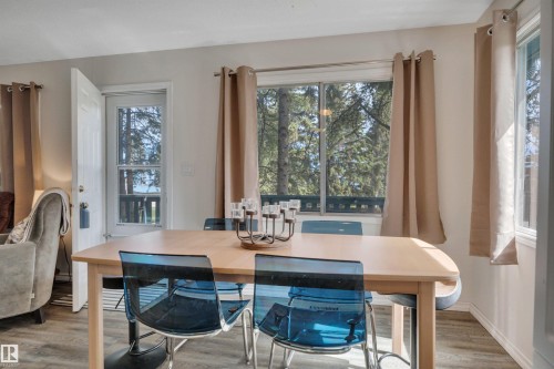 Dining area featuring wood-finish flooring, two large windows, a glass-paned door, and white baseboards - 305 3 St, Rural Wetaskiwin County, AB - Indoor Photo Showing Dining Room