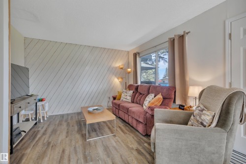 Living area featuring wood-finish flooring, a diagonally planked accent wall, and a large window - 305 3 St, Rural Wetaskiwin County, AB - Indoor Photo Showing Living Room