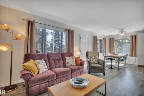 Living area with wood-finish flooring, multiple windows, and a ceiling fan - 305 3 St, Rural Wetaskiwin County, AB - Indoor Photo Showing Living Room