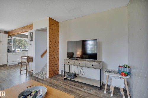 Wood-finish flooring throughout, featuring a natural wood beam and accent wall paneling - 305 3 St, Rural Wetaskiwin County, AB - Indoor Photo Showing Living Room